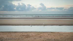 Une plage avec une vaste étendue de sable et une zone d’eau calme.