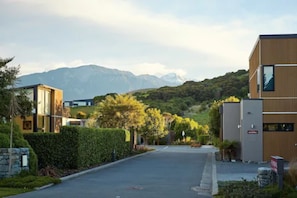 A modern building with a flat roof and large windows, surrounded by greenery and mountains in the background. - The Fairways Accommodation Kaikoura (Kaikoura)