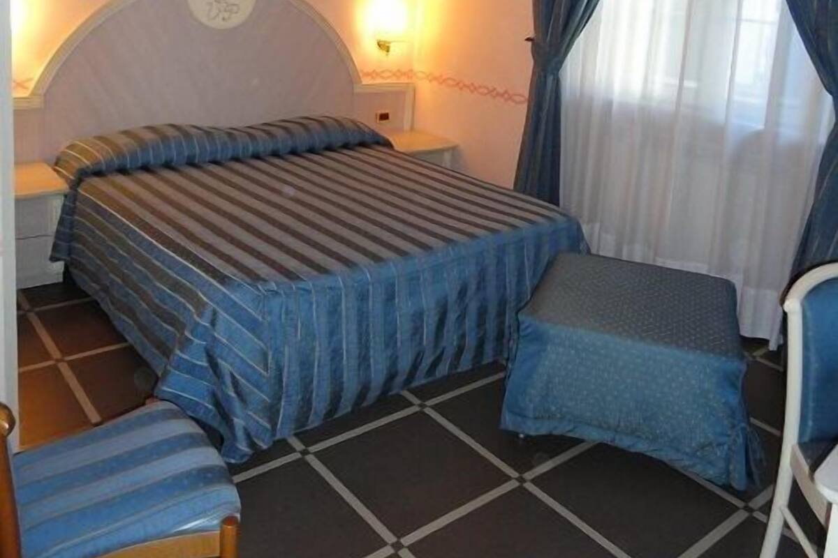 A hotel room with a bed, a chair, a small table, and a nightstand.