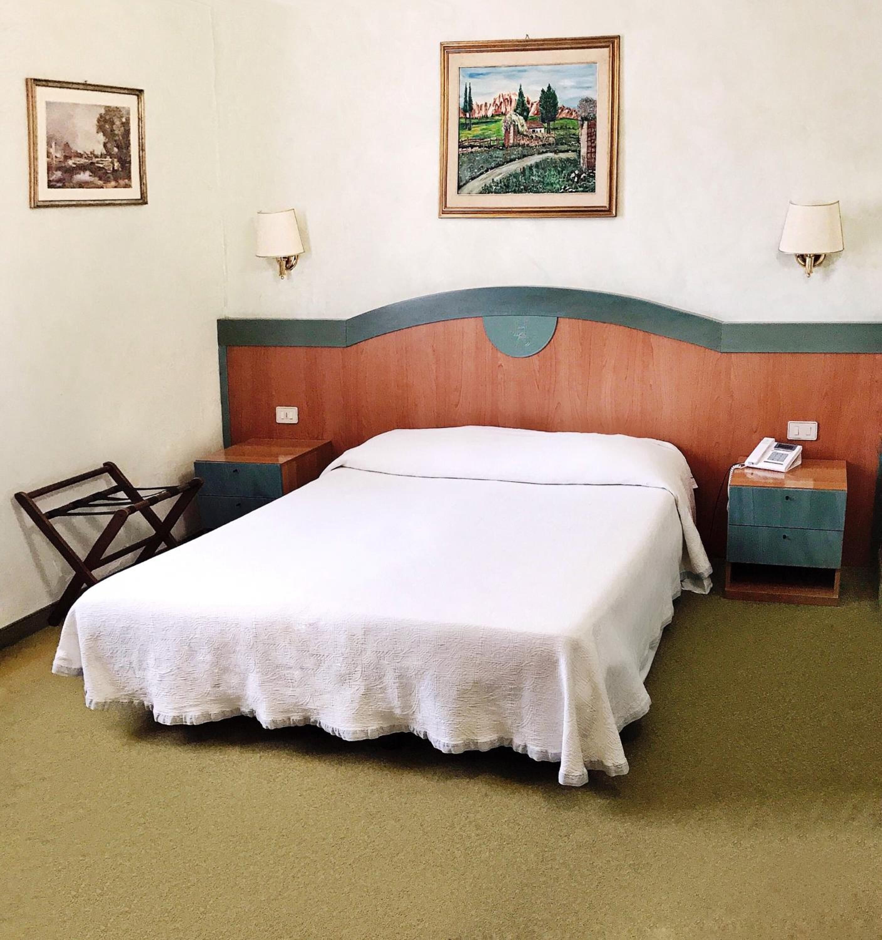 Ein Hotelzimmer mit einem großen Bett, zwei Nachttischen, einem Sessel und zwei Wandleuchten.