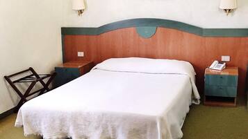 Ein Hotelzimmer mit einem großen Bett, zwei Nachttischen, einem Sessel und zwei Wandleuchten.
