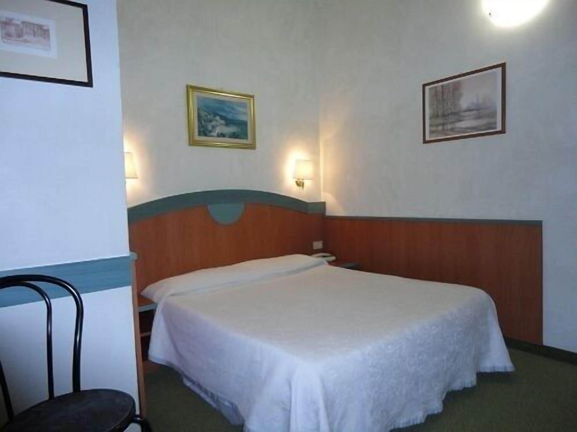 Ein Hotelzimmer mit einem Einzelbett, einem Sessel und zwei Wandleuchten.