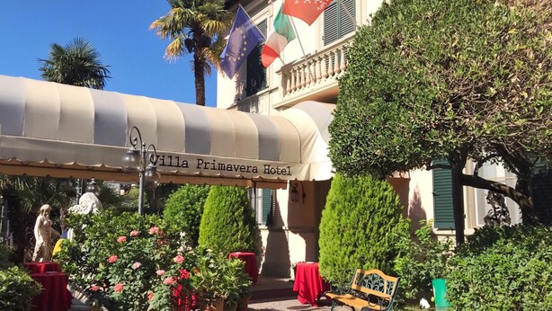 Hotel Villa Primavera con un área exterior techada, plantas en macetas y una banca.