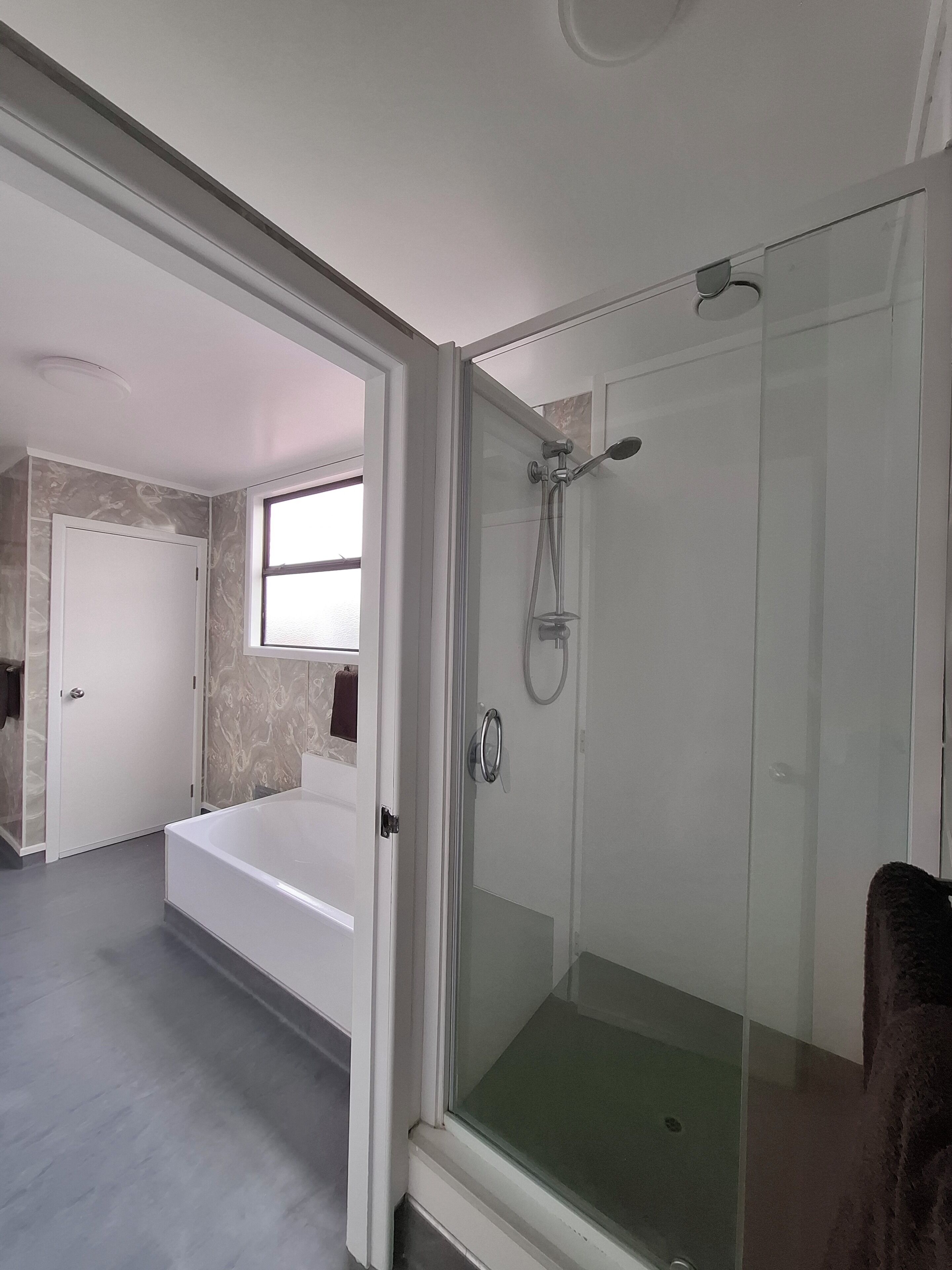 Un bany modern amb dutxa d'estuc de vidre, una banyera i un vàter.