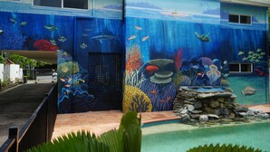 A building with an underwater mural, a pool, and a stone feature. - Port Douglas Motel (Port Douglas)