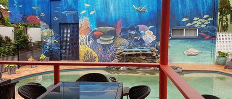 A pool area with a mural depicting an underwater scene, including fish and coral.