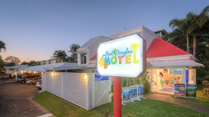 A motel with a signboard, a parking area, and a building with a red roof. - Port Douglas Motel (Port Douglas)