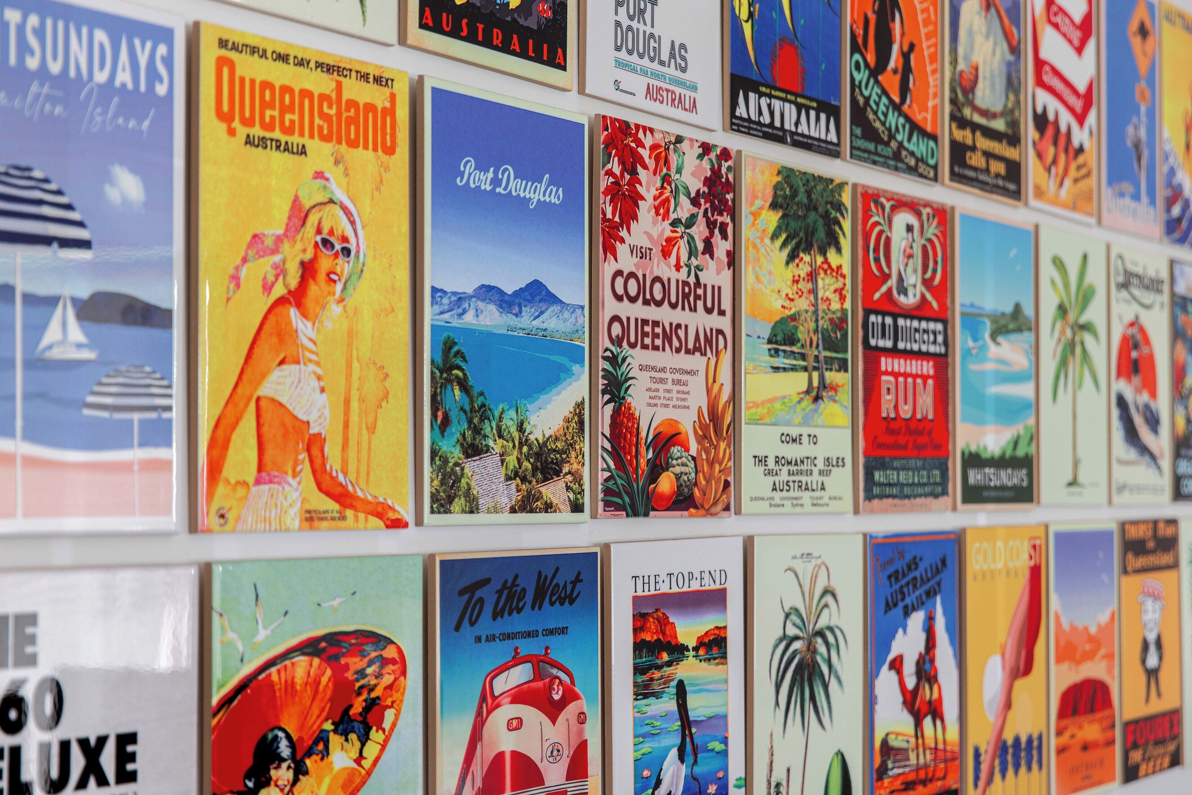 Una pared de carteles de viaje antiguos que publicitan varios destinos australianos.