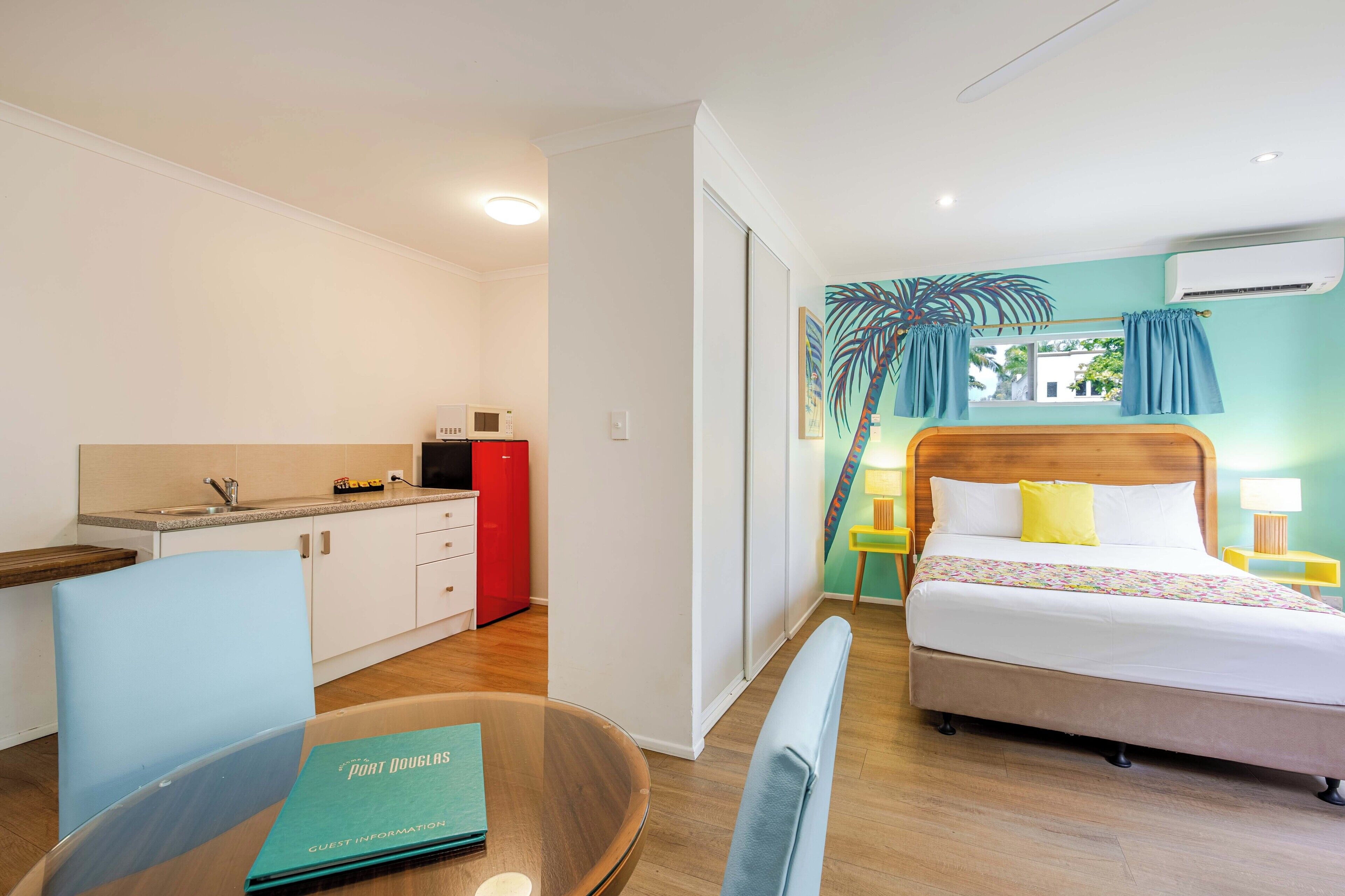 Een hotelkamer met een bed, een bureau met een stoel, een kleine kitchenette en een badkamer.