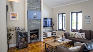 A living room with a fireplace, a television, a sofa, and a coffee table. - Orange Inn Knysna (Knysna)