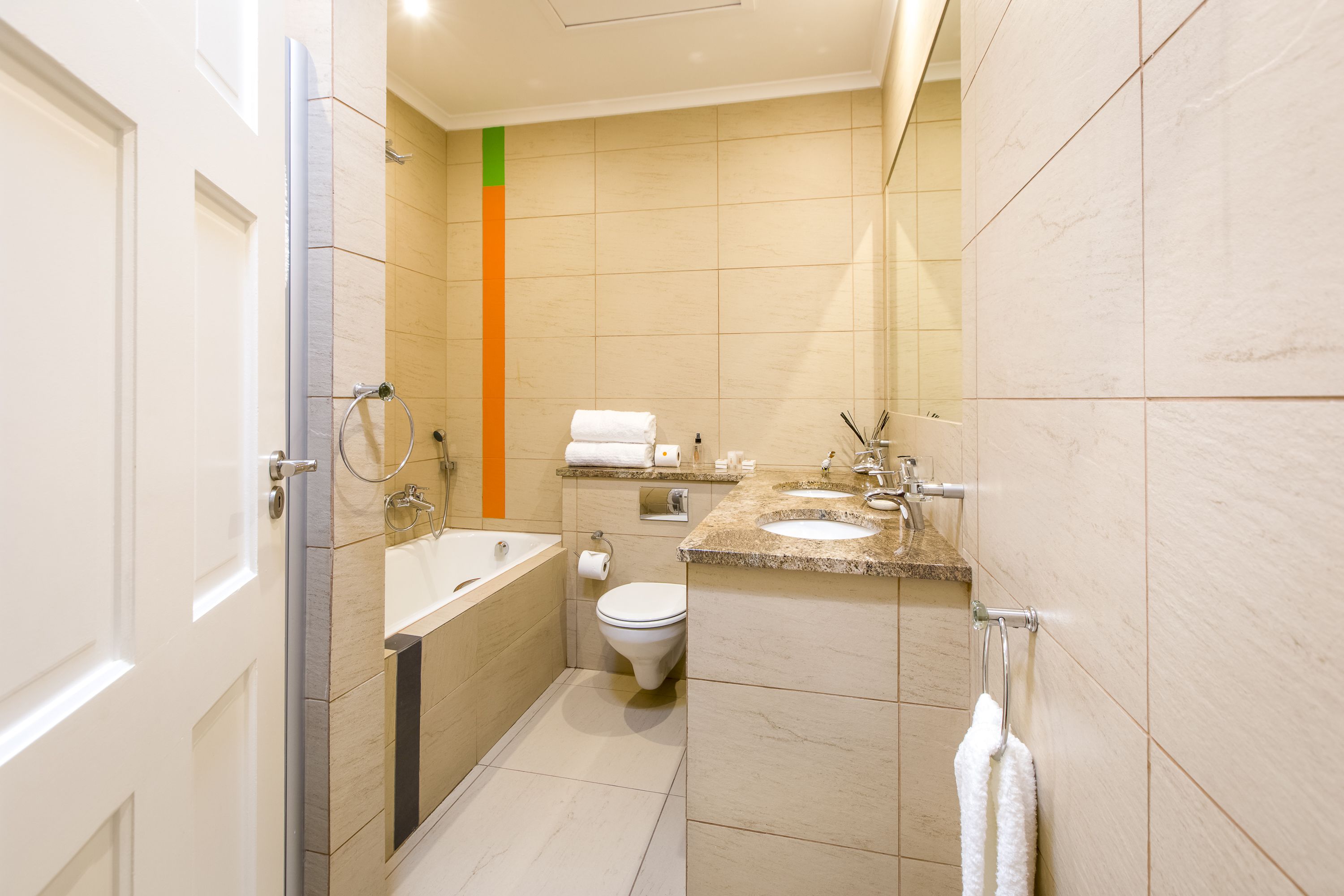 A modern bathroom with a bathtub, two sinks, a toilet, and a shower.