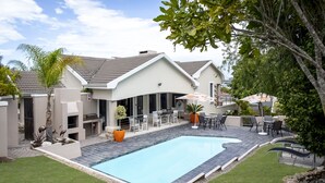 A modern house with a swimming pool, outdoor seating, and a patio area. - Orange Inn Knysna (Knysna)