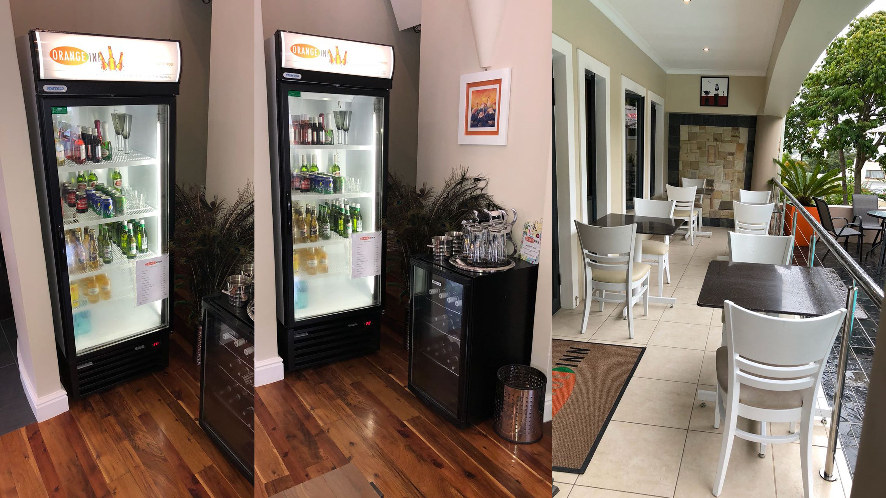 Un restaurante con dos refrigeradores llenos de bebidas, un comedor con sillas y mesas blancas, y una pluma de pavo real decorativa.