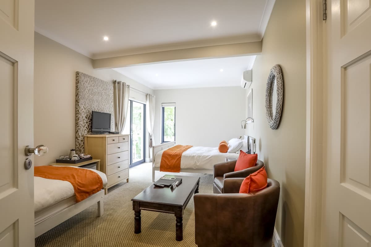 A hotel room with two beds, a desk, a chair, and a TV.