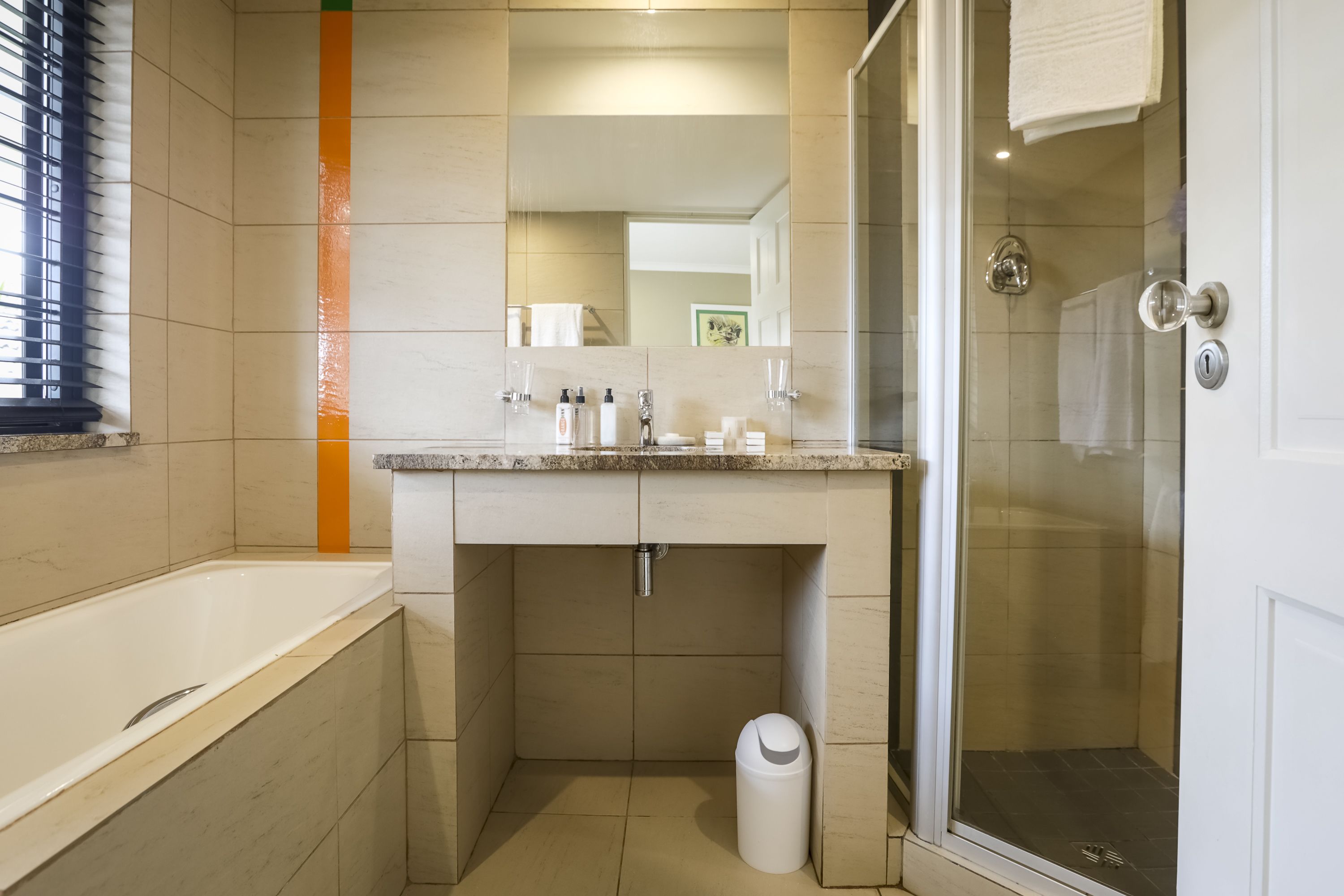 A modern bathroom with a bathtub, a glass-enclosed shower, and a vanity with a mirror.