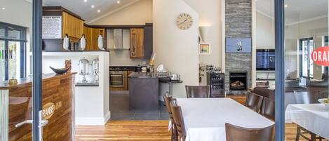 A modern kitchen with wooden cabinets, a central island, and a dining area with a white tablecloth.