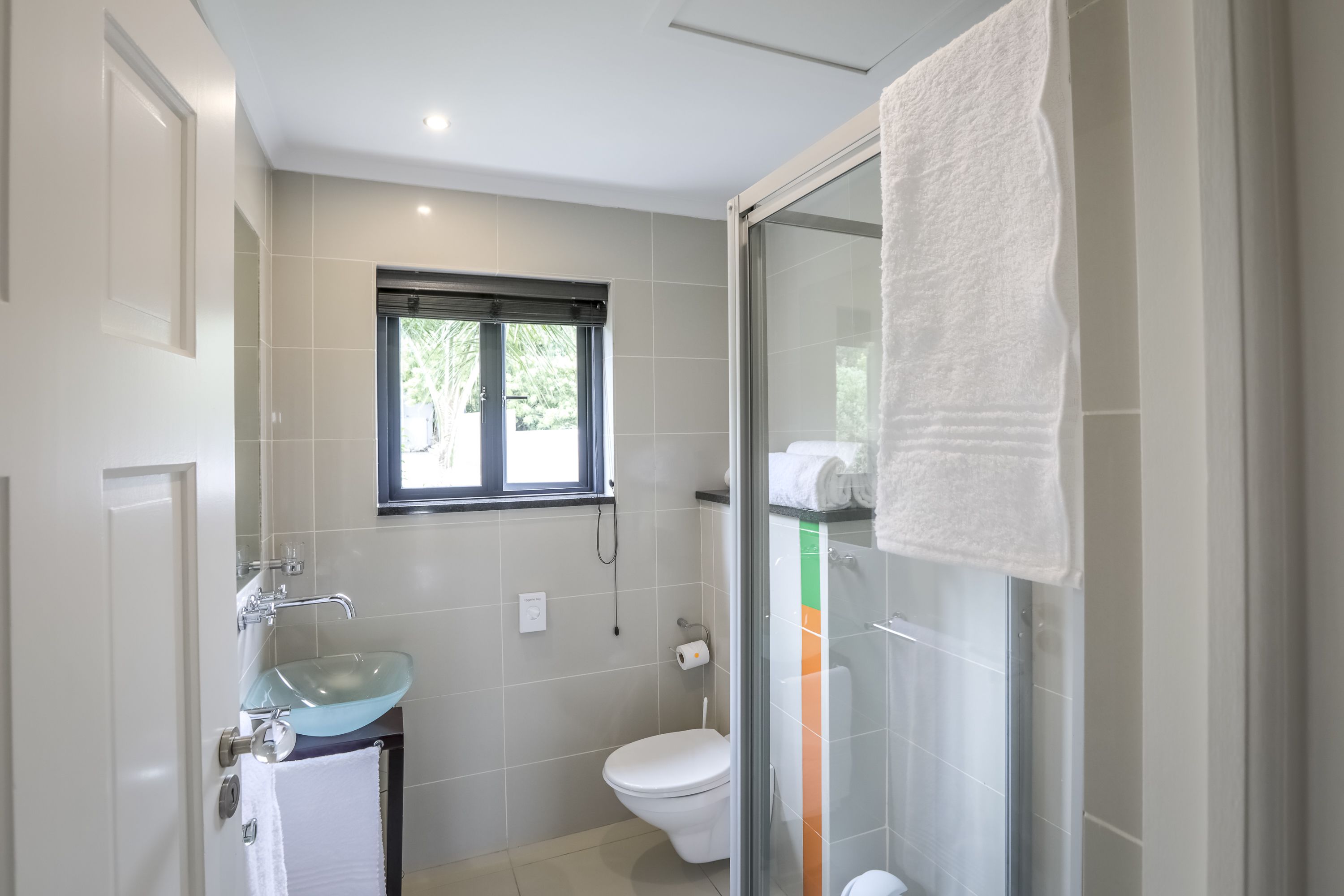 A modern bathroom with a glass shower enclosure, a white sink, and a toilet.