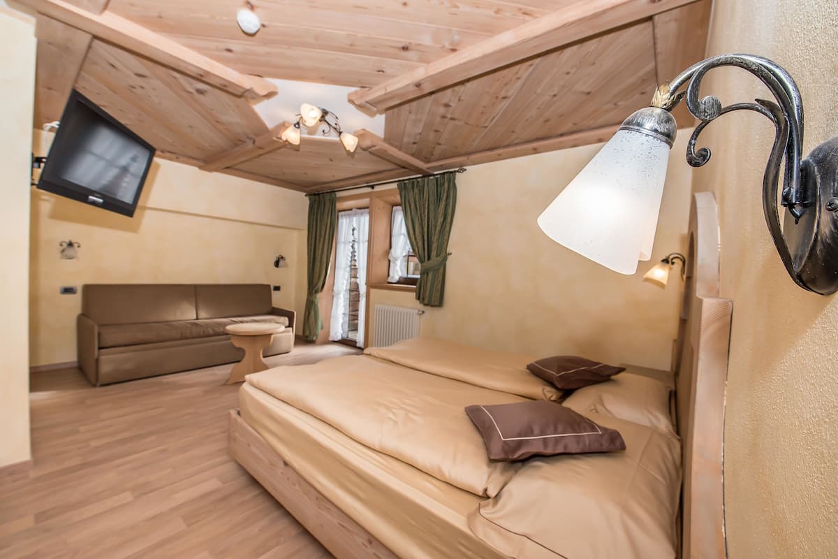 Un dormitorio con cama, sofá, televisor y lámpara.