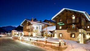 A snow-covered hotel with a sign reading "Hotel Capriolo" and a wooden exterior. - Hotel Capriolo (Livigno)