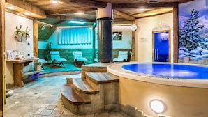 A spa area with a hot tub, wooden steps, and a mural of a snowy landscape. - Hotel Capriolo (Livigno)