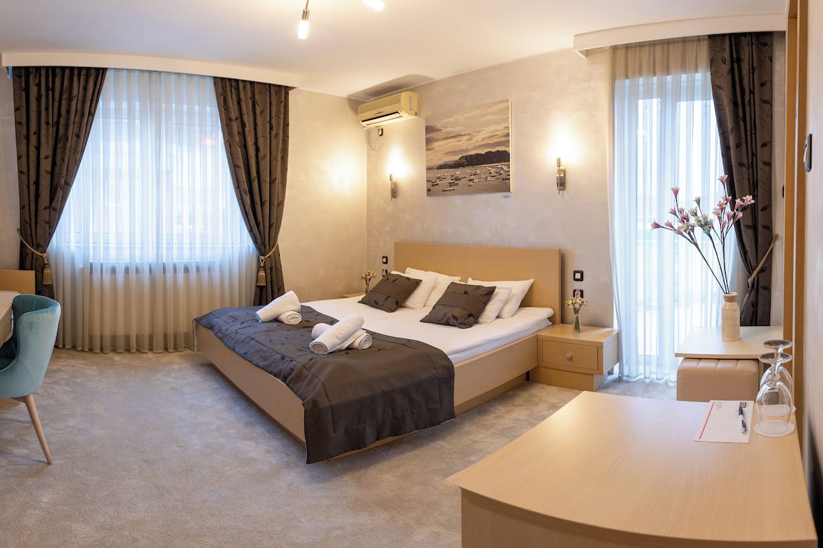 A hotel room with a bed, bedside tables, a desk, and a chair.