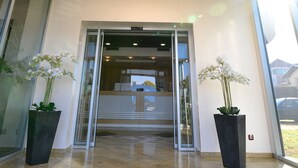 A hotel entrance with a circular skylight, a reception desk, and potted plants. - Euro Garni Hotel (Belgrade)