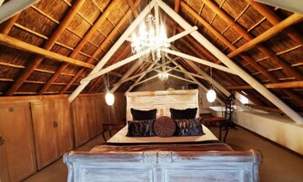Quarto com teto de madeira abobadado, cama com várias almofadas e um candelabro.