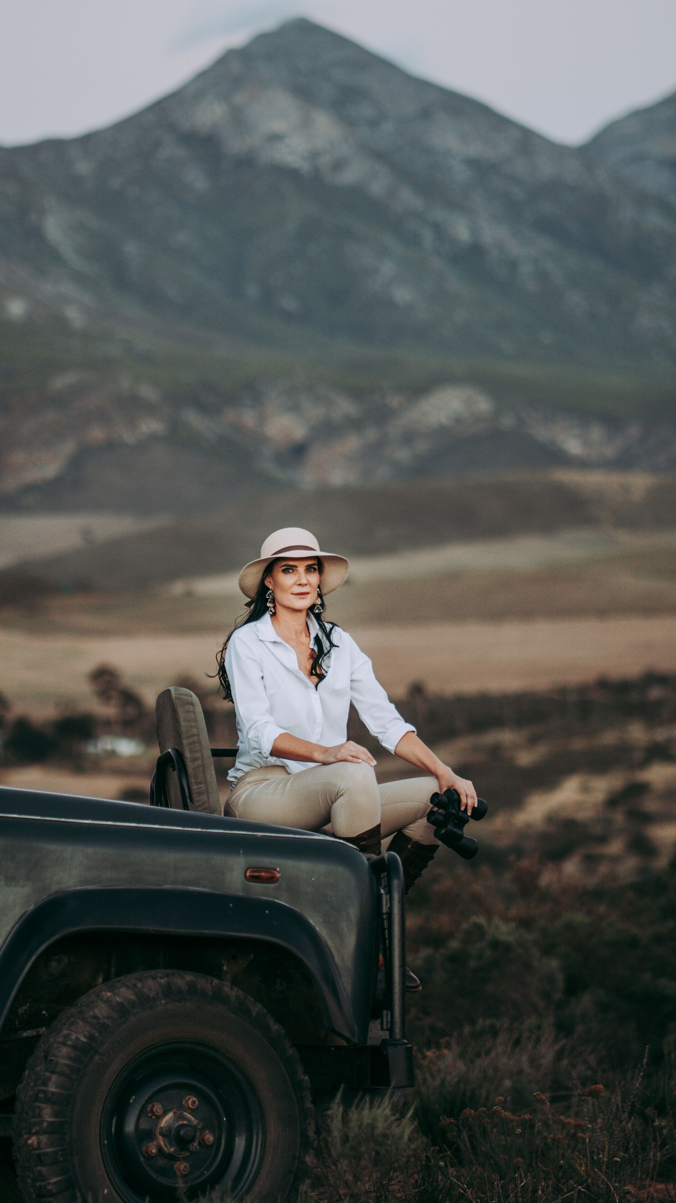 Una persona sentada en un vehículo en un paisaje natural con montañas al fondo.