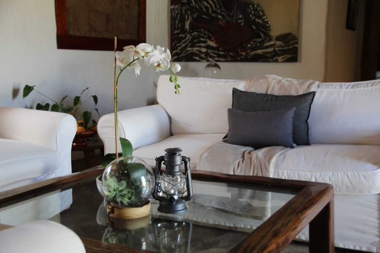Un salon avec un canapé blanc, une table basse en verre et une lanterne décorative.