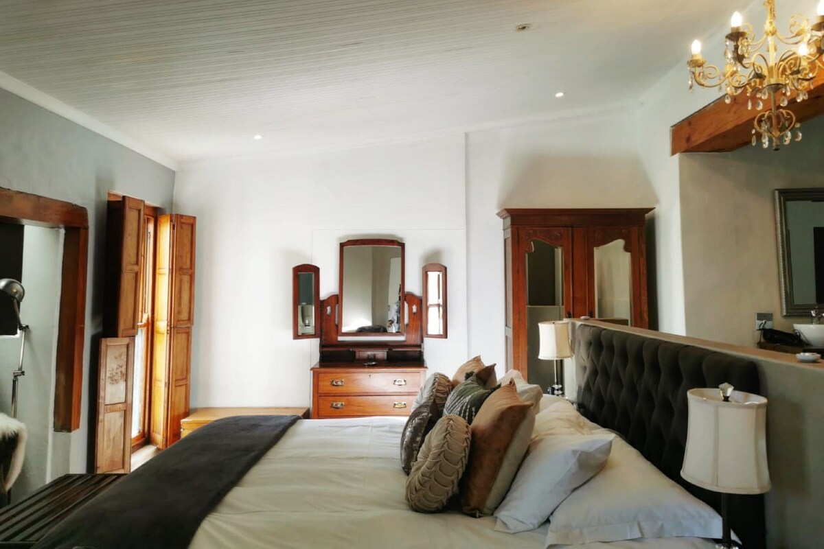 Ein Schlafzimmer mit einem großen Bett, einem Holzkleiderschrank und einem Spiegel.