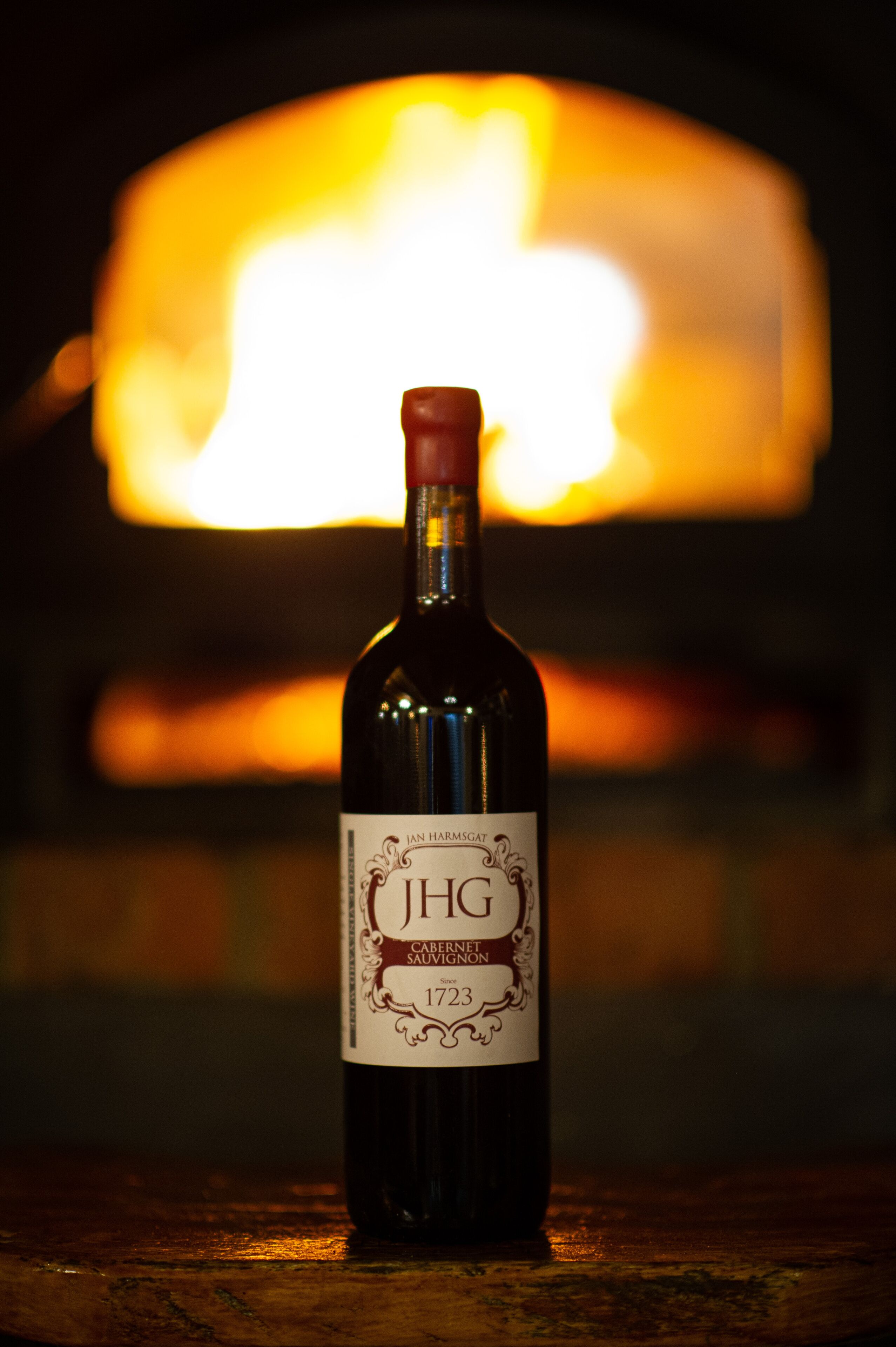 Una botella de vino con etiqueta frente a una chimenea.