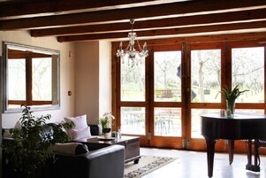 Uma sala de estar com um piano, um sofá e um lustre.