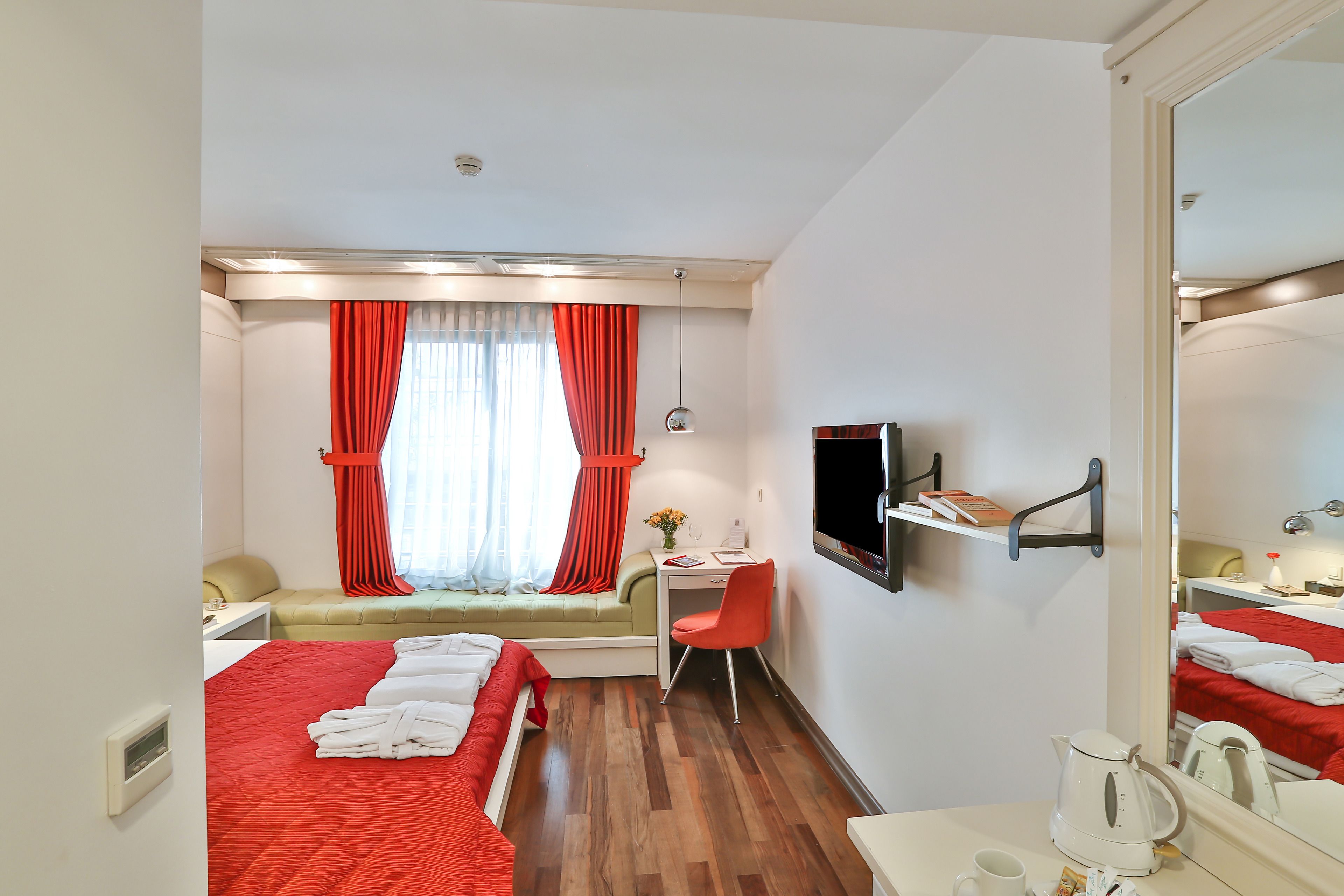 A hotel room with two beds, a desk, a chair, a TV, and a mirror.
