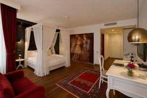 A hotel room with a four-poster bed, a red armchair, a desk with a mirror, and a large painting on the wall. - Senatus Hotel - Special Class (Istanbul)