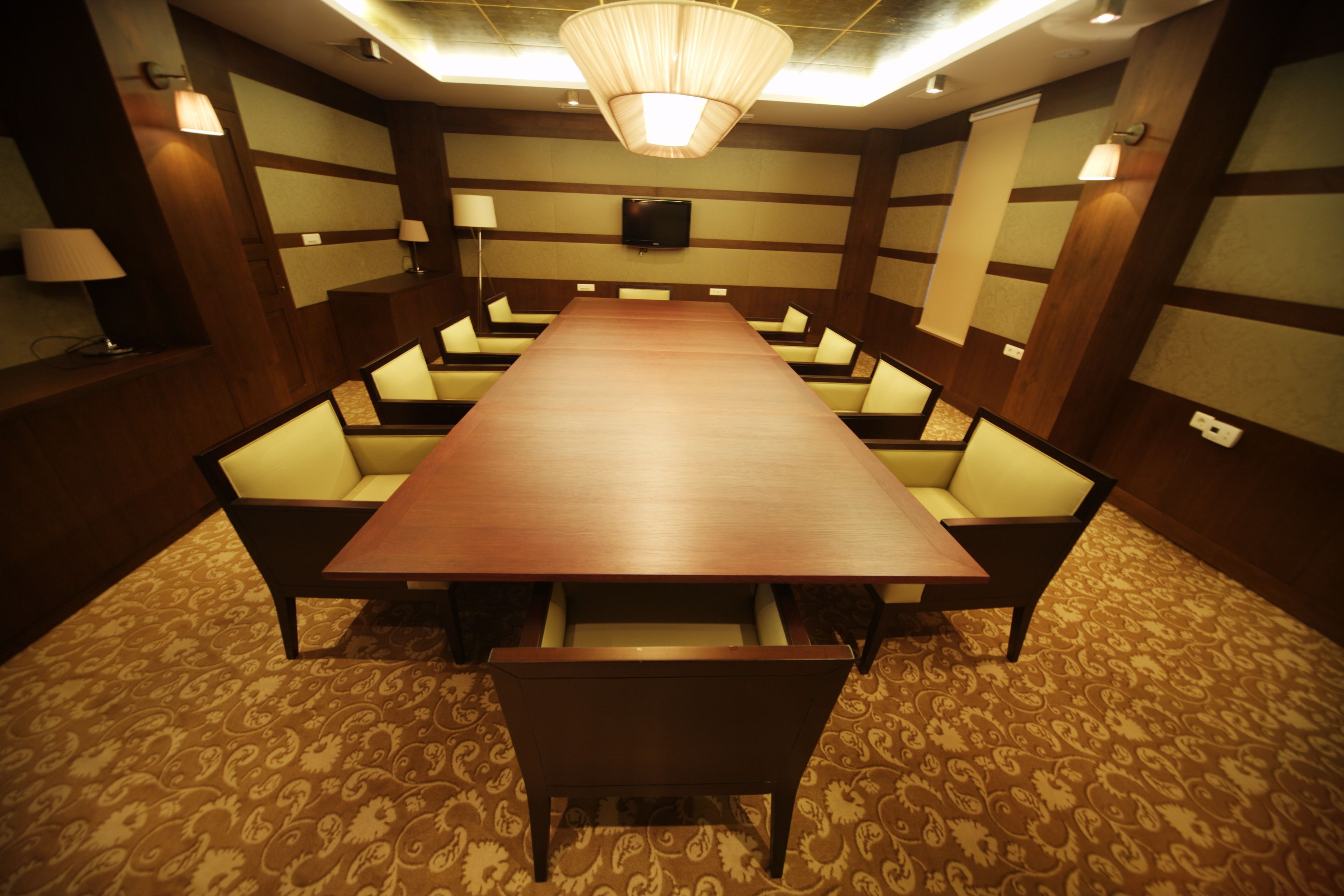 A conference room with a long table, multiple chairs, and a television screen on the wall.