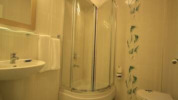 A bathroom with a glass-enclosed shower, a sink, and a toilet.