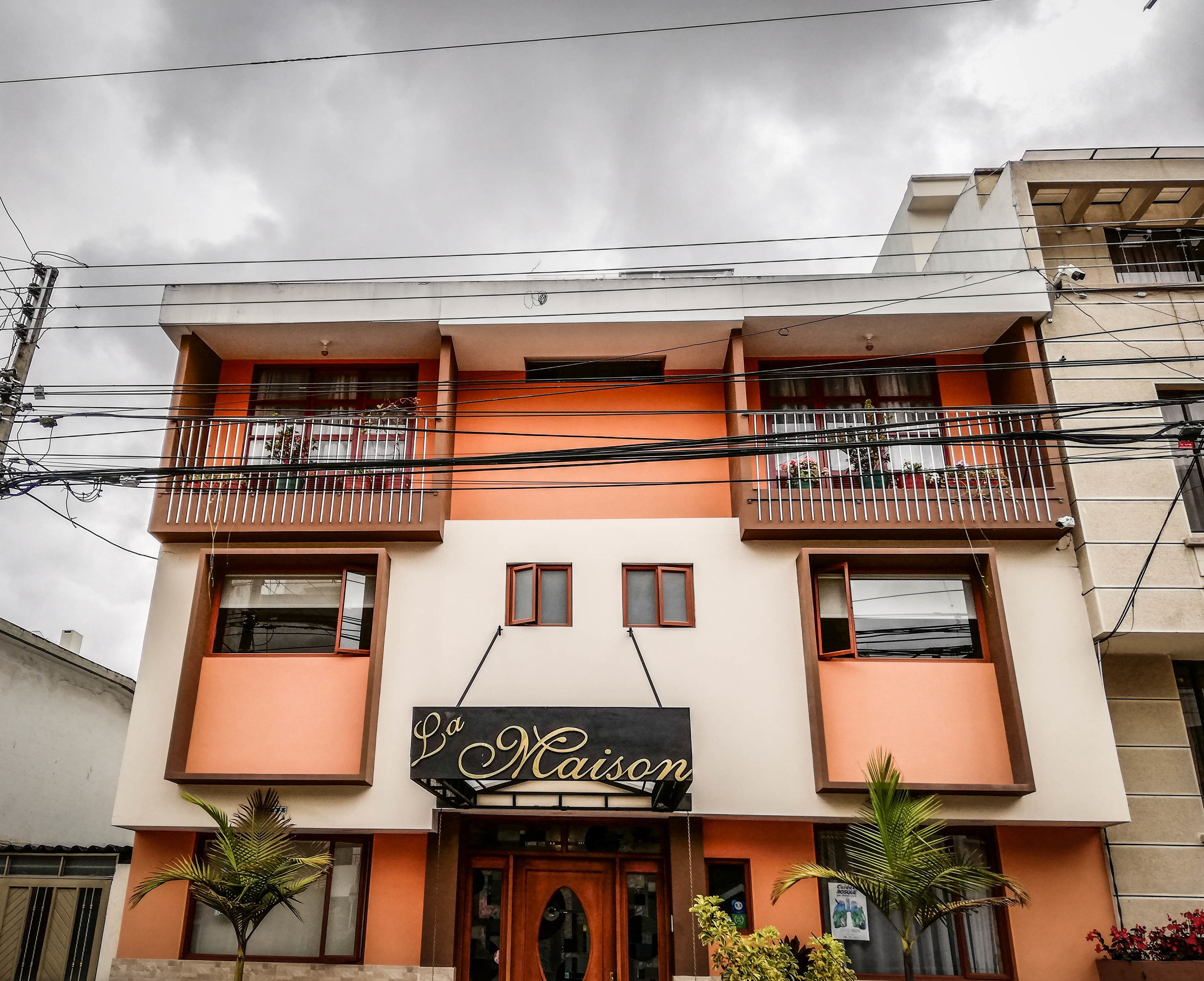 Un edificio de dos pisos con balcones y un cartel que dice "La Maison".