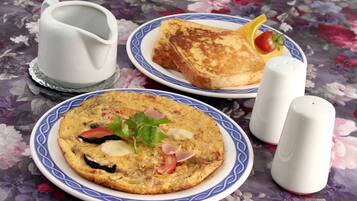 Two plates of food, one with toast and the other with an omelette, on a floral tablecloth.