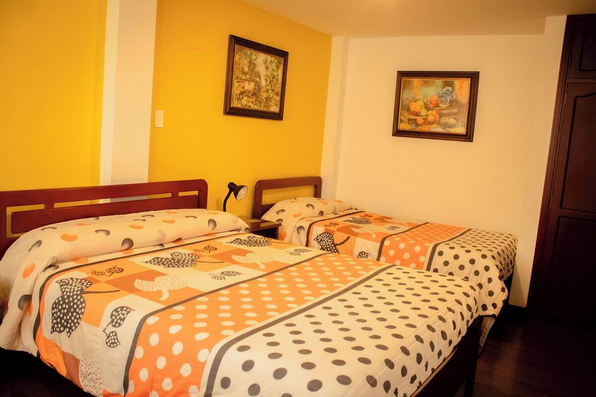 Een kamer met twee bedden, elk met stippenbeddengoed, een houten hoofdbord en een nachtkastje met een lamp.