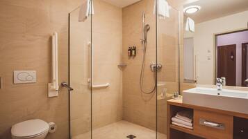 A modern bathroom with a glass-enclosed shower, a toilet, and a vanity with a mirror.