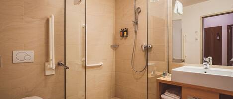 Un baño moderno con ducha envuelta en cristal, inodoro y tocador con espejo.