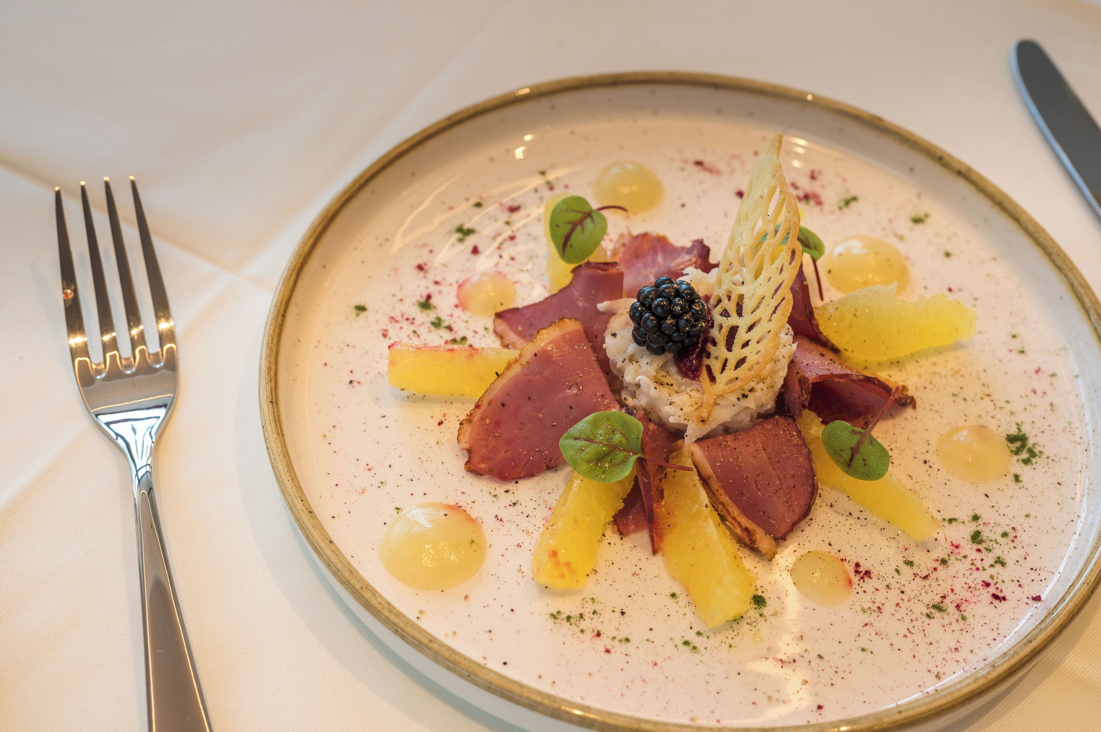 A plate of food with various ingredients, including meat, fruit, and a decorative element.