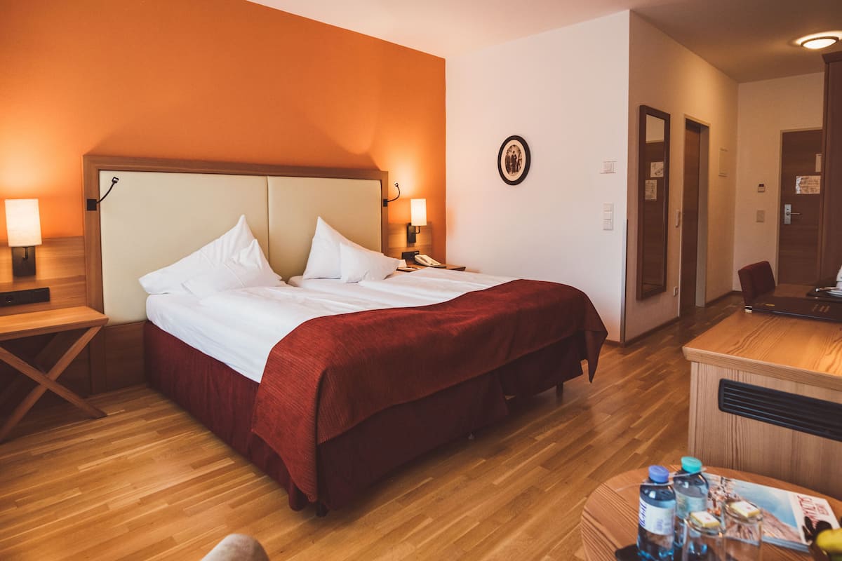 Ein Hotelzimmer mit Bett, Nachttischen, einem Schreibtisch und einer Rezeption.
