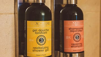 Two L'OCCITANE shower gel dispensers mounted on a wall.