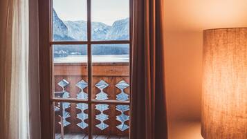 Ein Fenster mit Blick auf Berge, ein Holzbalkon und eine Lampe.
