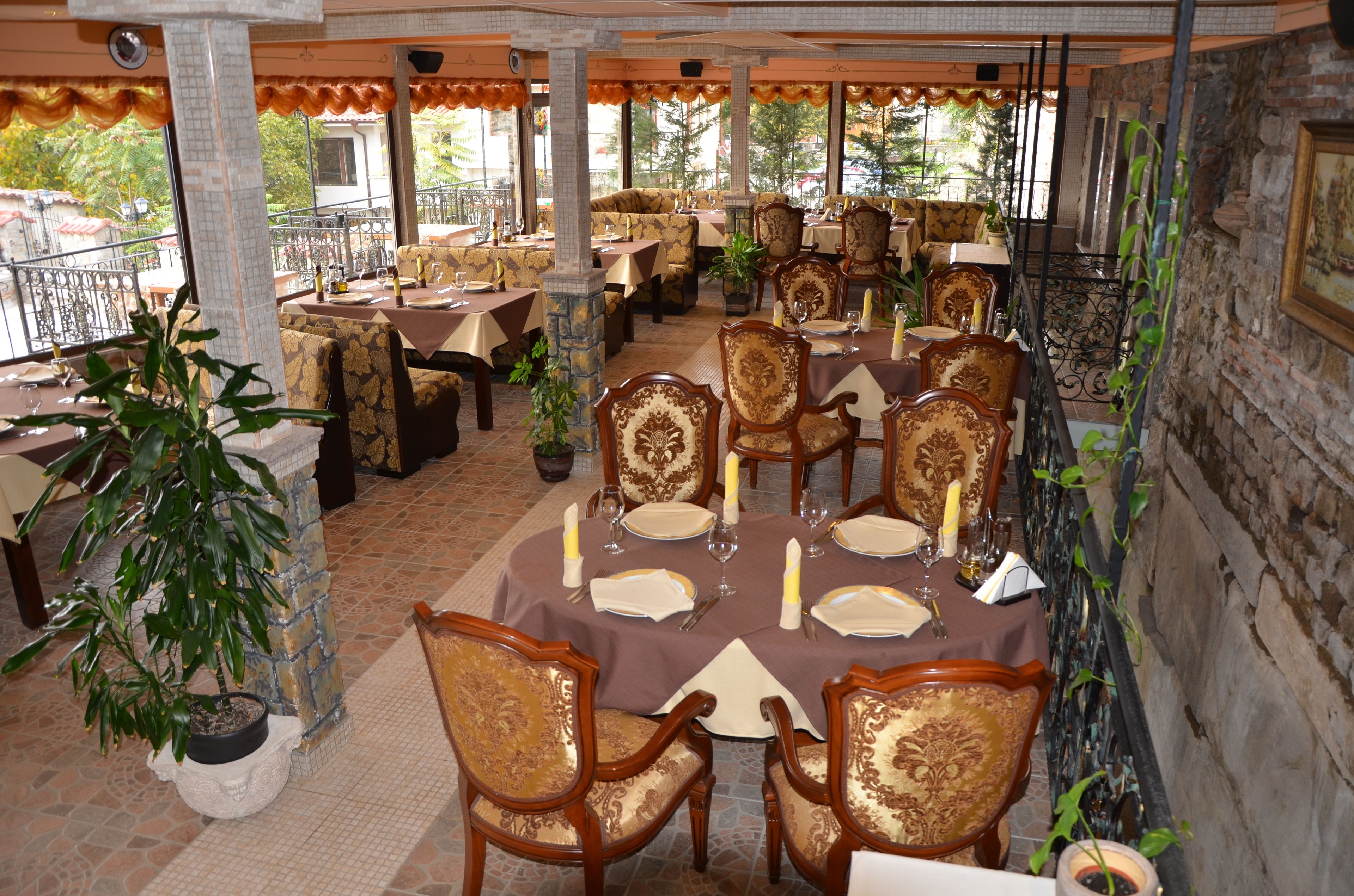 A restaurant with round tables, chairs, and potted plants.