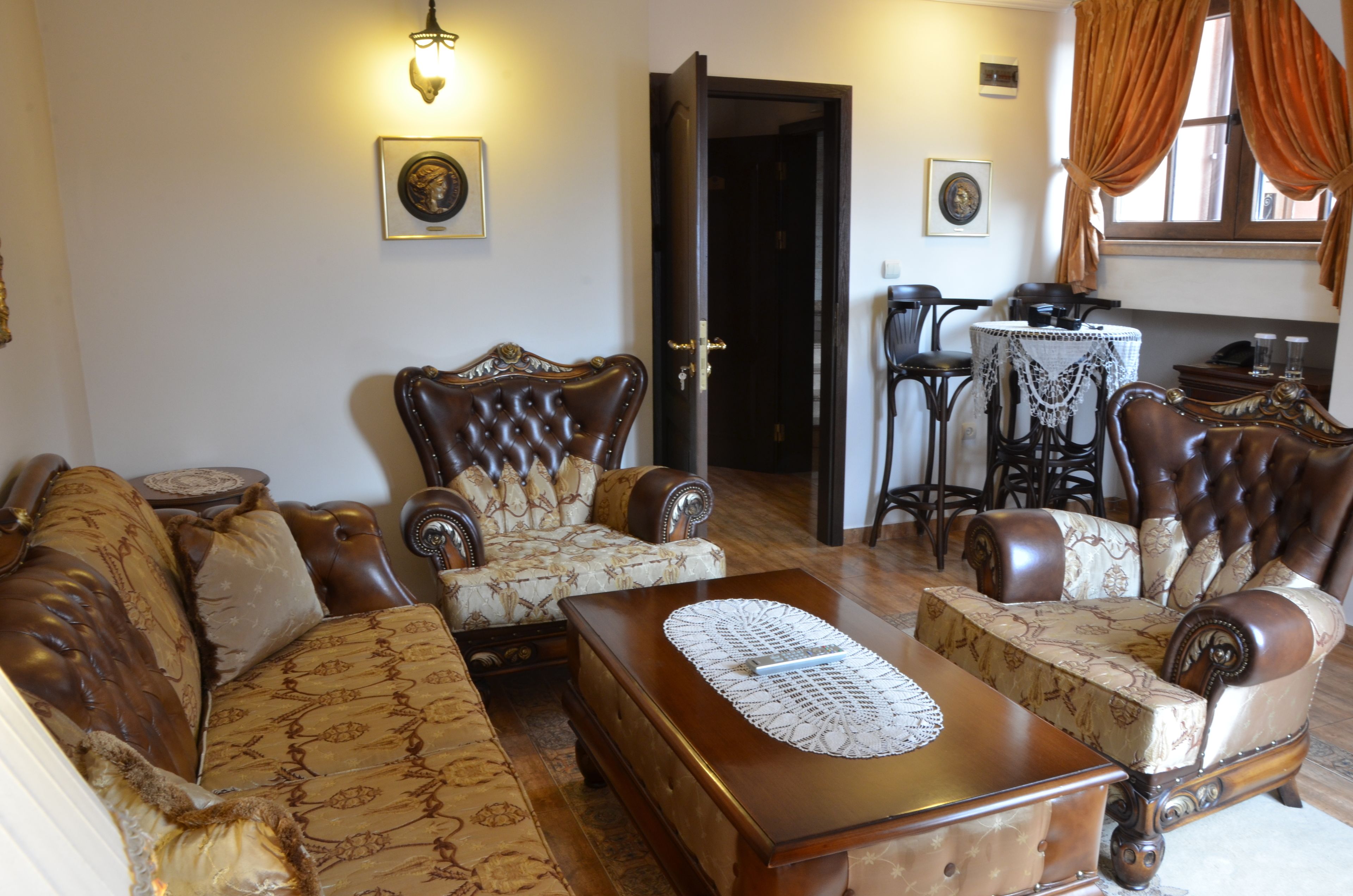 Una sala de estar con un sofá, dos sillones, una mesa de centro y una mesa de comedor con sillas.