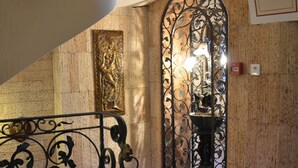A grand staircase with ornate metal railings, a marble floor, and a wall-mounted sculpture. - Boris Palace Boutique Hotel & Winery (Plovdiv)