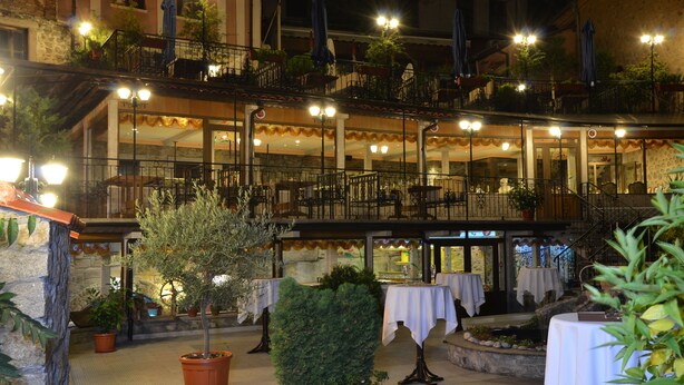 An outdoor dining area with multiple tables and chairs, surrounded by potted plants and a stone wall. - Boris Palace Boutique Hotel & Winery (Plovdiv)