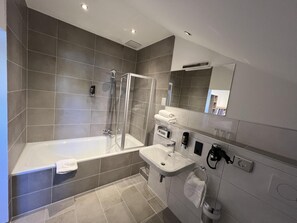 A modern bathroom with a bathtub, shower, and sink.